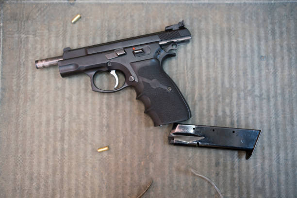 istock Hands carefully disassembling a black handgun on a wooden table during maintenance or repair 2196144976