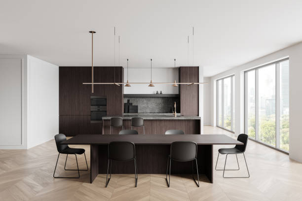 istock Modern kitchen and dining room interior with dark wood accents, minimalist lighting, and large windows in a bright and open space. 3D Rendering 2196145580