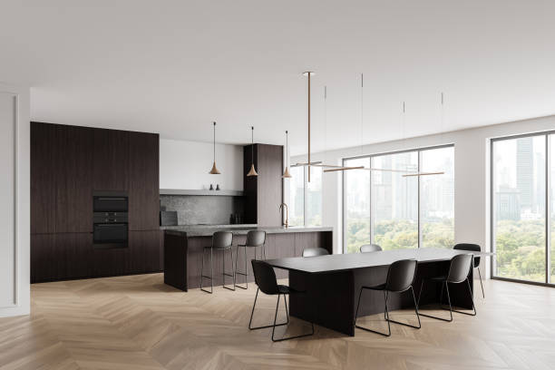 istock Modern kitchen interior with dark cabinets, island, dining table, large windows, and cityscape view. 3D Rendering 2196146765