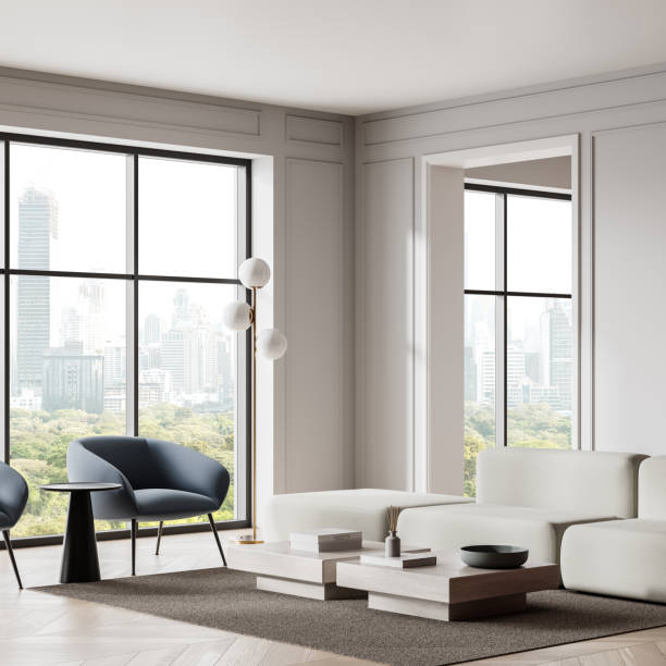 istock Modern living room with white sofa, blue chairs, and cityscape view through large windows. 3D Rendering 2196146967