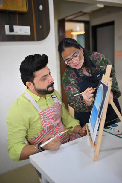 istock Artisan demonstrating canvas painting techniques to mid-adult man 2196148171