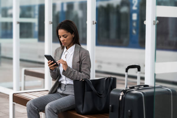 istock Young businesswoman using phone while waiting for train on railway station. 2196150487
