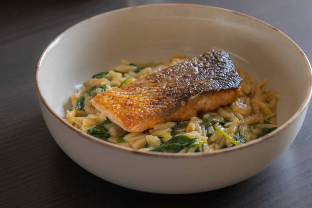 istock Delicious cooked salmon filet served with orzo pasta and spinach in a bowl 2196152019