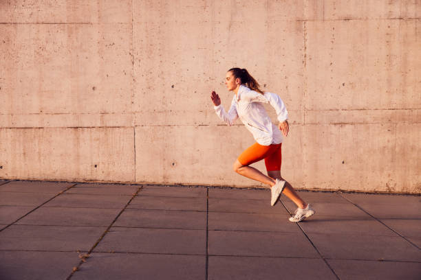 istock Fit woman running outdoors against concrete wall 2196152072