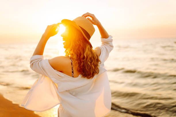 Young woman enjoys her vacation on the beach. Seascape at sunset with beautiful sky. Travel, weekend, relax and lifestyle concept.
