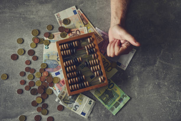 istock Man counting money on gray table with abacus and euro banknotes 2196153246