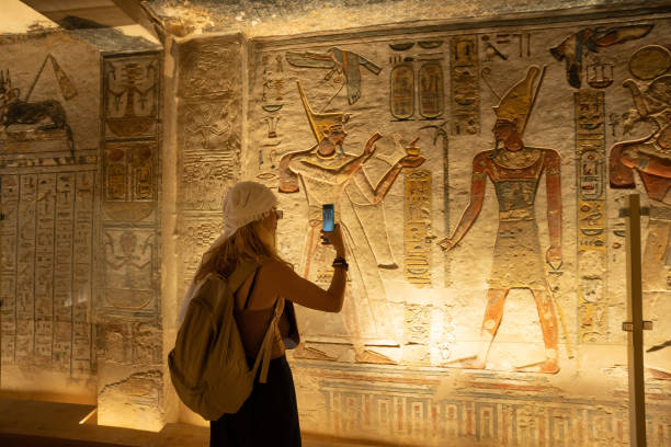 istock Woman using smartphone and taking picture while visiting the inner rooms inside the Tomb of Ramses IX, KV6 at Valley of Kings,Luxor,Egypt 2196153874