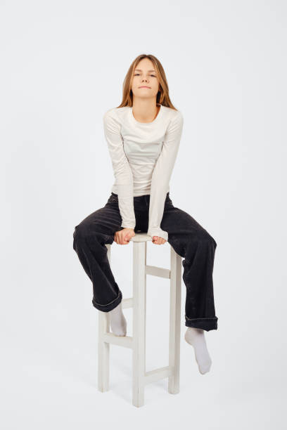 istock Young woman sitting on a stool, showcasing a casual and confident posture 2196158319