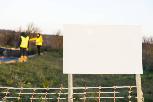 Two archaeologists wearing safety vests working at an archaeological site, taking notes and measurements.