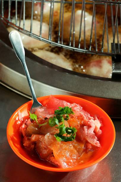 Marinated fish in vibrant orange bowl with herbs.