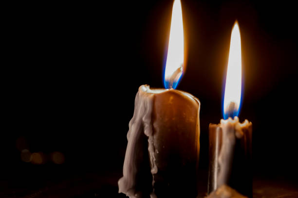 black candles on a black background. Candles with Flames in Dark Setting. Magic and esotericism