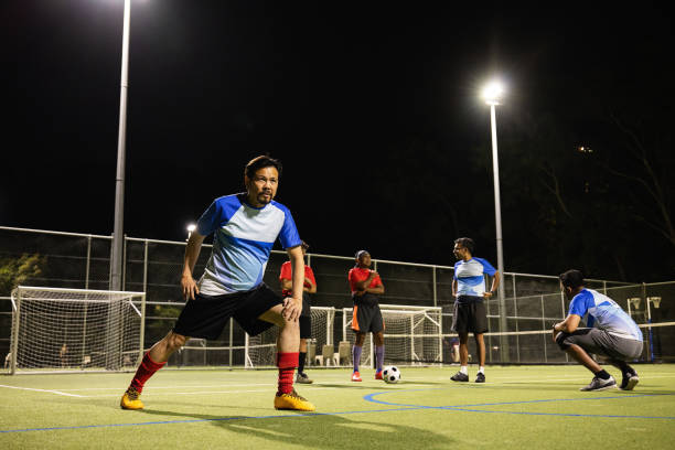 istock Group of Men Stretching Before a Soccer Match on a Lit Field at Night 2196163681