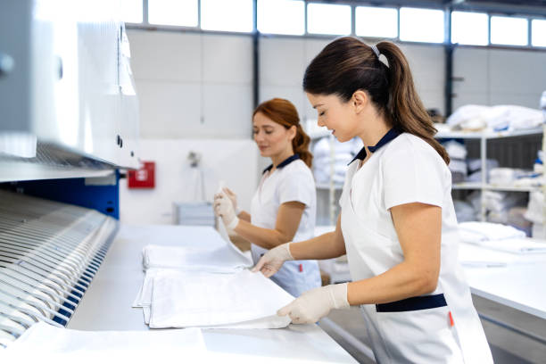 istock Female workers folding clean laundry after ironing in dry cleaning service. 2196163812