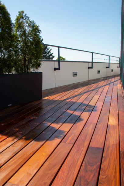 istock Bright sunny day reveals polished wooden deck on a modern balcony with greenery and blue sky 2196168256