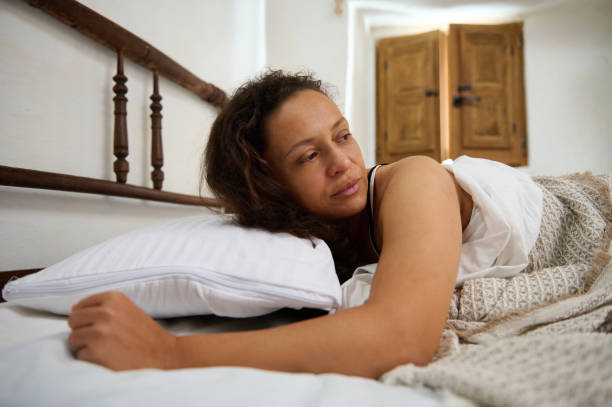 istock A woman lying pensively in bed during the early morning light 2196170081