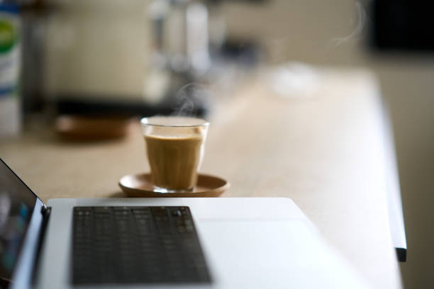 Hot coffee sits beside a laptop on a kitchen counter, ready for a productive work-from-home morning
