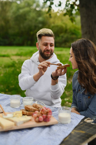 istock Male Showing Affection to Girlfriend Making Her Try His Sandwich Specialty on Picnic 2196171999