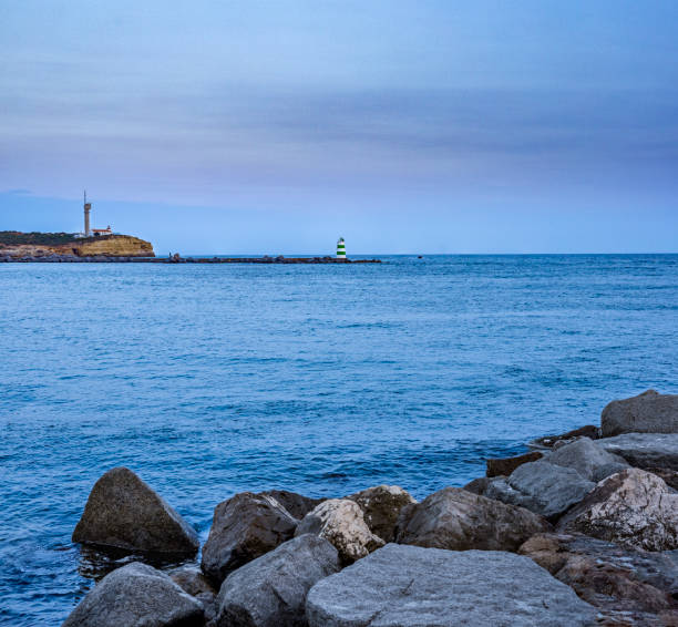 View of one fisher boat approaching the lighthouse of Andijk under a moody sky. Drone shot.