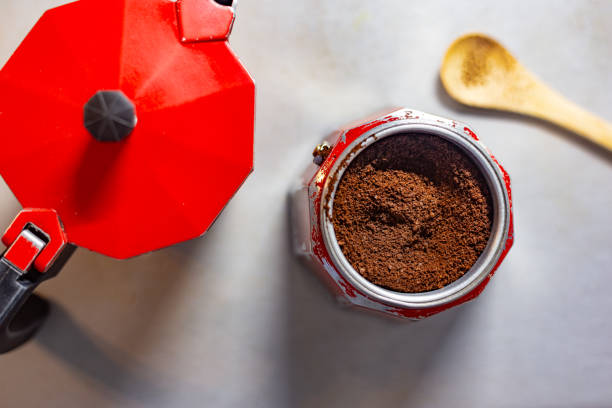 Preparing coffee with red moka pot and ground coffee beans