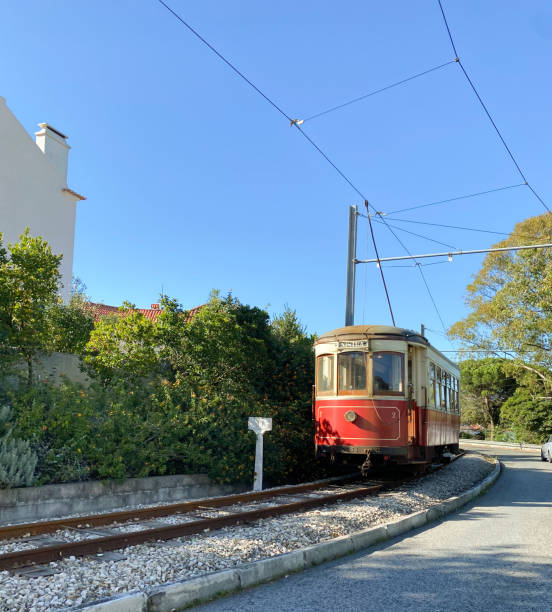 istock Red vintage tram on a railway track surrounded by greenery and a clear blue sky. 2196174011