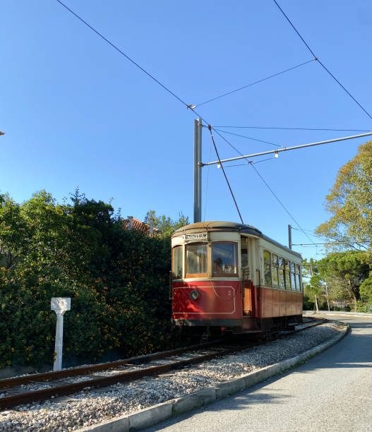 istock Red vintage tram on a railway track surrounded by greenery and a clear blue sky. 2196174012