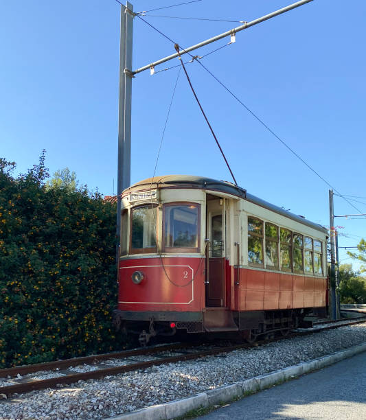 istock Red vintage tram on a railway track surrounded by greenery and a clear blue sky. 2196174024