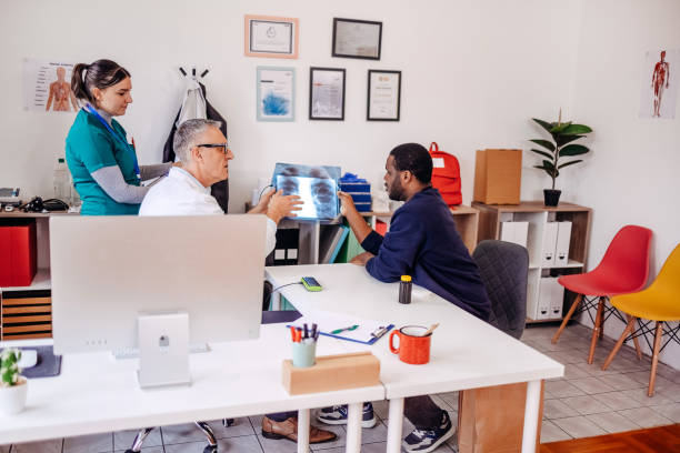 istock Doctor showing X-ray image to a patient in office while checking his health status with medical assistant around 2196180508