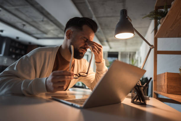 istock Man working remotely, overwhelmed by fatigue and a headache 2196183975