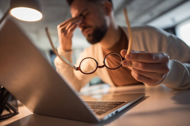 istock Man working remotely, overwhelmed by fatigue and a headache 2196183993