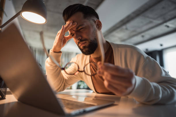 istock Man working remotely, overwhelmed by fatigue and a headache 2196184037