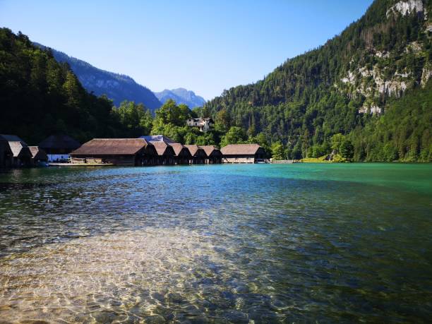 Scenic view of boathouses on Lake Konigssee with clear water and lush green mountains in Bavaria, Germany.