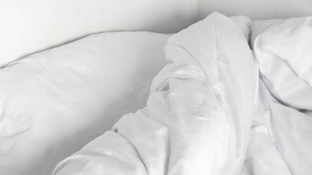 istock Soft and fluffy white linens on an unmade bed, highlighting minimalist design 2196189077