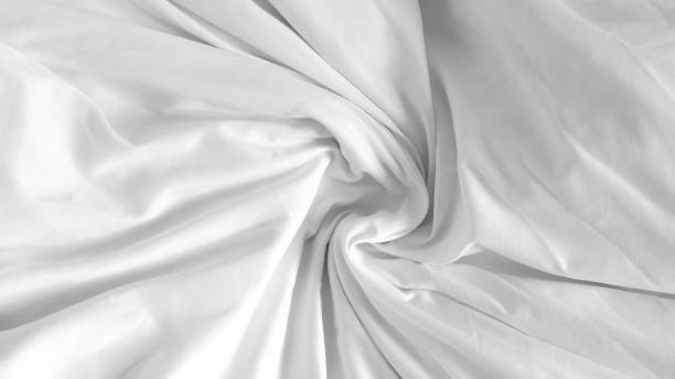 Soft and fluffy white linens on an unmade bed, highlighting minimalist design
