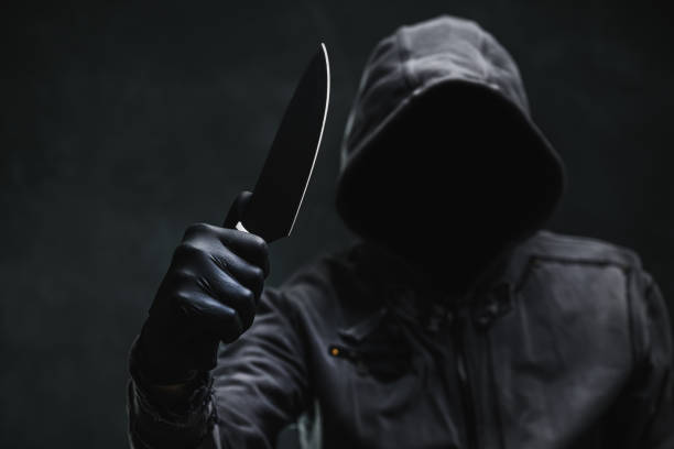 istock Sinister hooded criminal with sharp knife weapon 2196193316