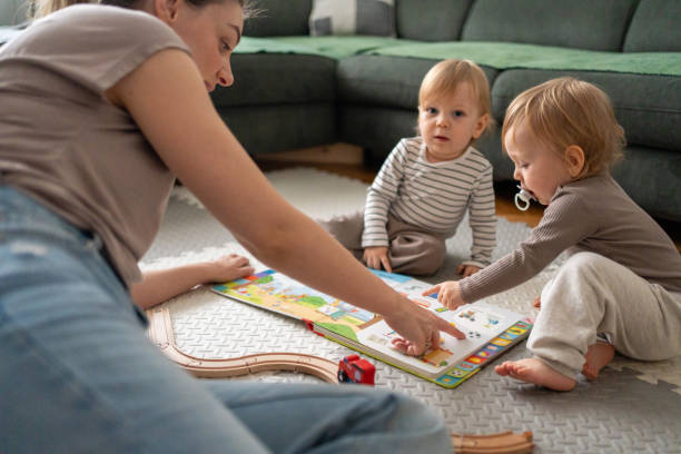 istock Identical twins reading picture book with mother at home 2196197205