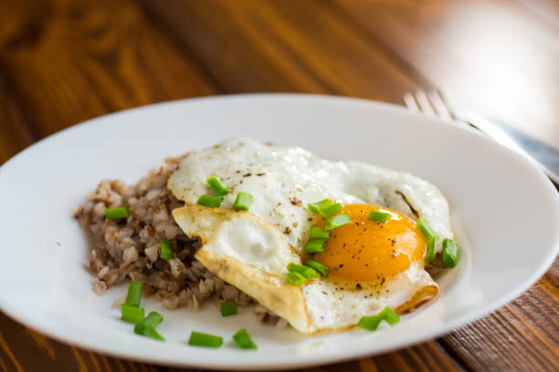 istock Fried eggs with boiled buckwheat and onions on a wooden table 2196197552