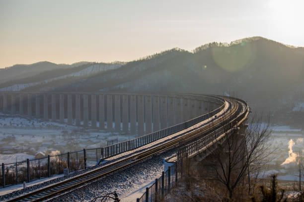 Smoke rises in the early morning, and the train viaduct in the countryside in winter