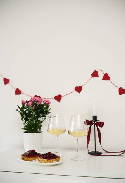 istock Valentines day table setting red roses and wine glasses, candle, plates with fruit cakes on white background. Valentine 's greeting card - Image 2196199704