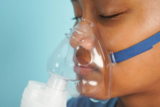 istock Little Girl Undergoing Nebulizer Therapy on Blue Background 2196201157