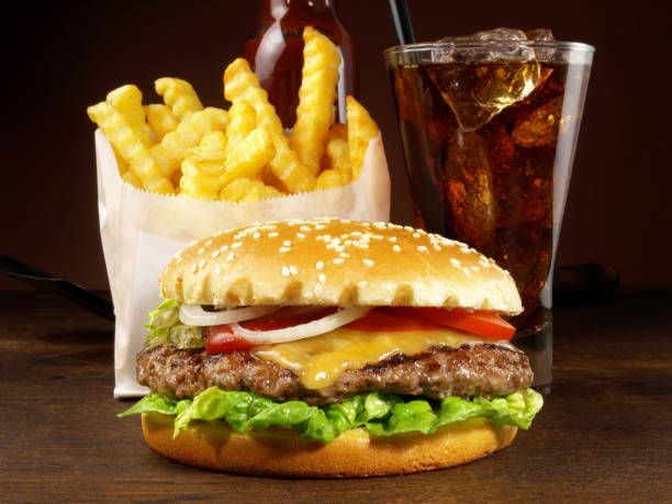 A delicious beef hamburger with crispy french fries served on a wooden plate.