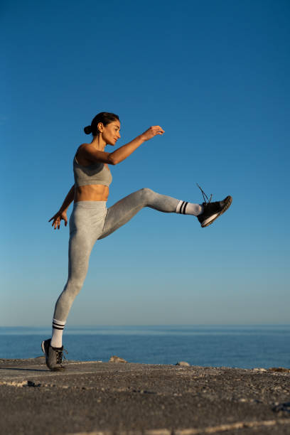istock Dynamic outdoor workout: woman performing high kick exercise by the sea 2196202671