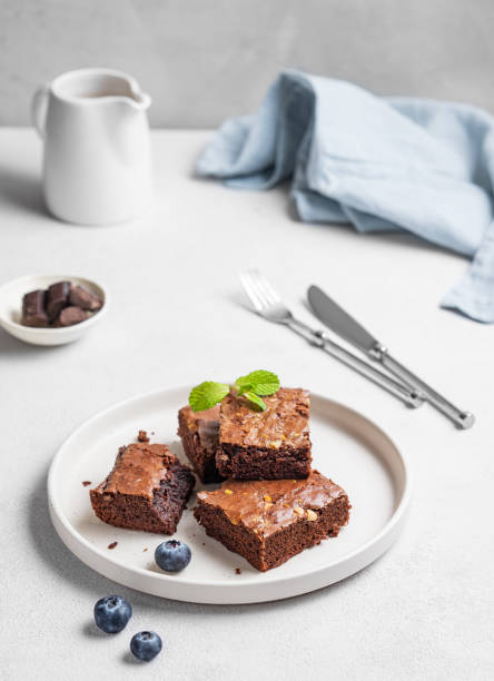 istock Chocolate brownie with nuts cut into pieces on a plate with blueberry and mint  on a light background 2196204832