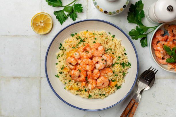 istock Mediterranean Couscous with fried Shrimps, yellow tomatoes, onion, parsley. White table surface. Top view, copy space. 2196205396