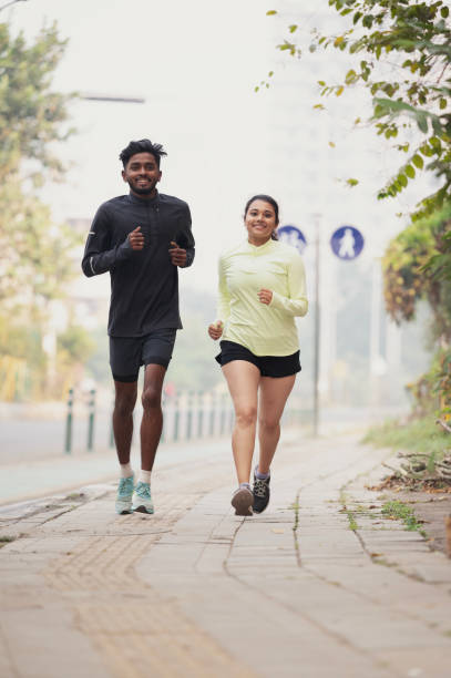 istock Young Couple Jogging on an Urban Pathway 2196205899