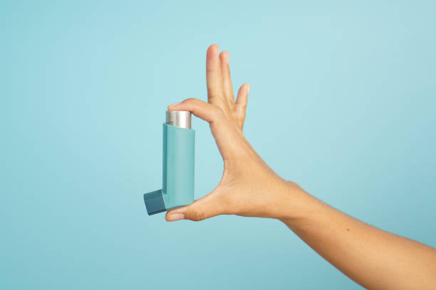 istock Isolated Hand holding inhaler on blue background 2196208079