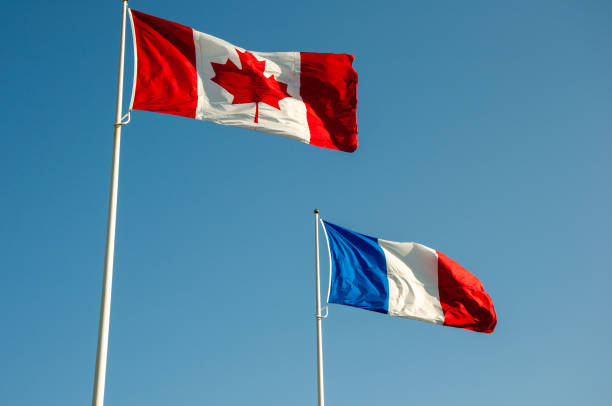 istock Canadian and French flags fly in clear sky. 2196210332