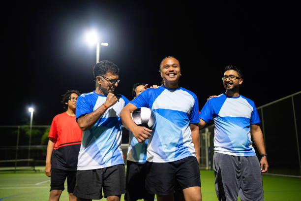 istock Team Enjoying Friendly Football Game Under Night Lights 2196212785