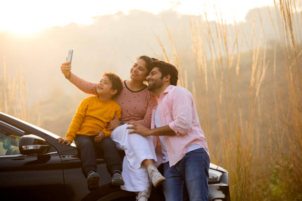 Happy family taking selfie over mobile phone during sunset