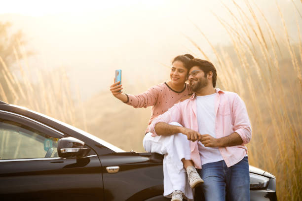 istock Young couple taking selfie over mobile phone by car 2196215461