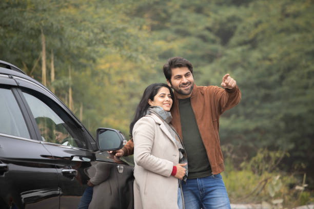 istock Man pointing and woman looking away while standing by car 2196215831